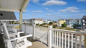 A wooden deck with white railings and a view of a residential area with houses and a clear sky. - Phelps: Semi-oceanfront w/private pool, hot tub, rec and media room & elevator! (Nags Head)