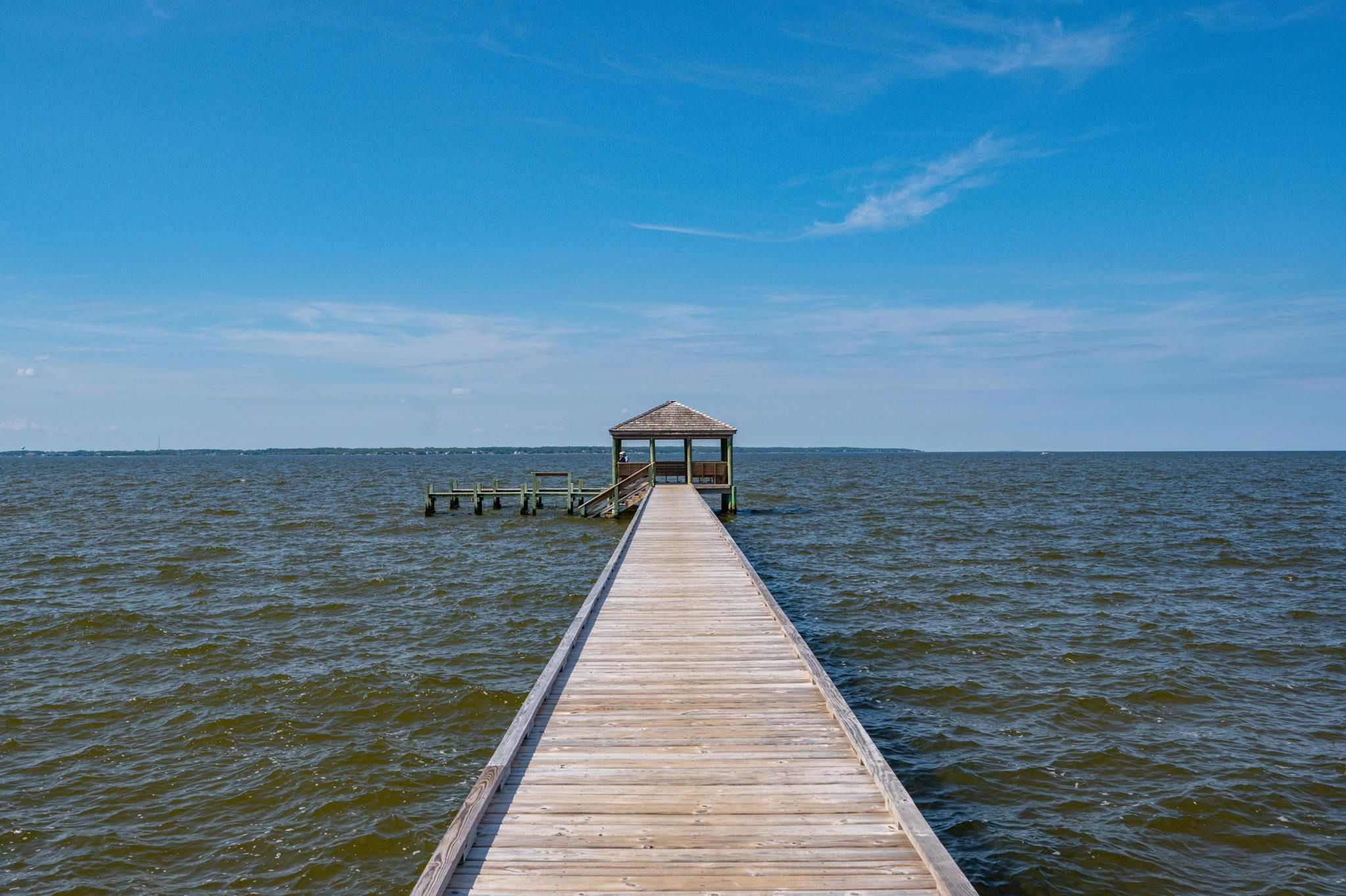 A wooden pier leading to a gazebo over water.