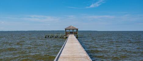 A wooden pier leading to a gazebo over water.