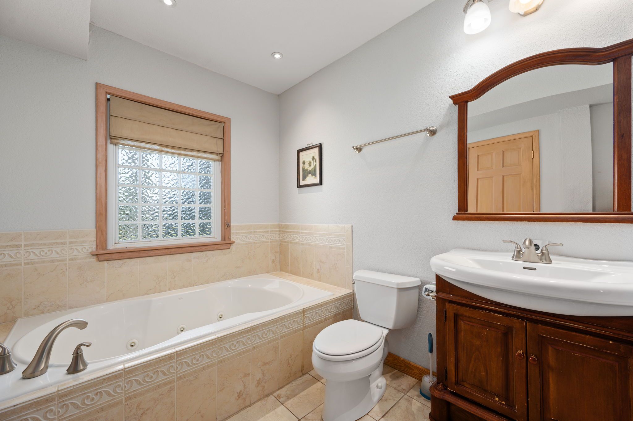 A bathroom with a bathtub, toilet, vanity, and a large mirror.