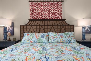 Un lit avec une couette à motifs floraux, une tête de lit décorée et deux lampes de chevet.
