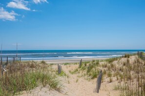 Une plage avec des dunes de sable et une clôture en bois.