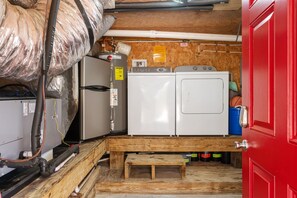 A compact laundry room with a washing machine, dryer, and a red door. - At Ease: Ocean views, short walk to the beach, close to fishing pier. (Nags Head)