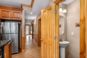 Una cocina con armarios de madera, un refrigerador de acero inoxidable y un lavabo con un espejo arriba.