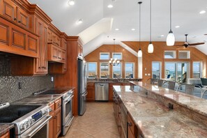 A spacious kitchen with wooden cabinets, a large island, and a view of the ocean.