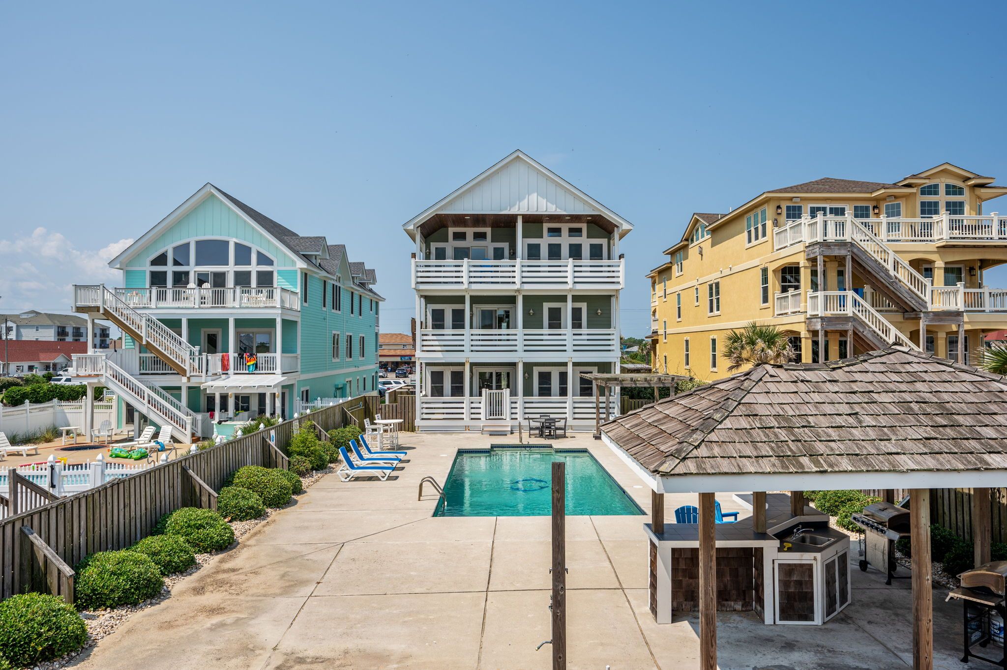 A beachfront property with a swimming pool, multiple balconies, and a covered outdoor area.