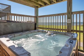 A hot tub with a view of a golf course and the sea.