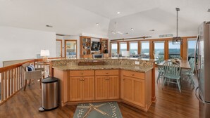 A spacious kitchen with wooden cabinets, granite countertops, and a view of the ocean. - Sunset Shack: Soundfront, great sunsets, hot tub, community pool & tennis courts (Nags Head)