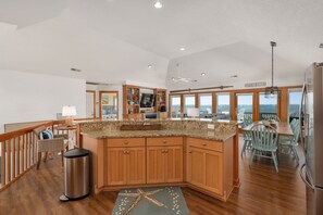 A spacious kitchen with wooden cabinets, a granite countertop, and a view to the outside. - Sunset Shack: Soundfront, great sunsets, hot tub, community pool & tennis courts (Nags Head)