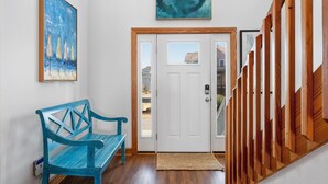 A hallway with a wooden bench, a white door, and a wooden wall panel. - Sunset Shack: Soundfront, great sunsets, hot tub, community pool & tennis courts (Nags Head)