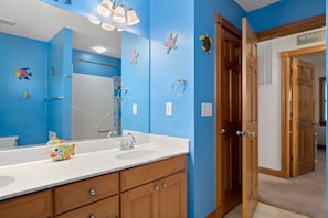 Un baño con paredes azules, armarios de madera, un espejo grande y un lavamanos.