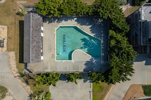 An aerial view of a swimming pool with the words "Sisters" on the water's edge, surrounded by trees and a building with a sloped roof.