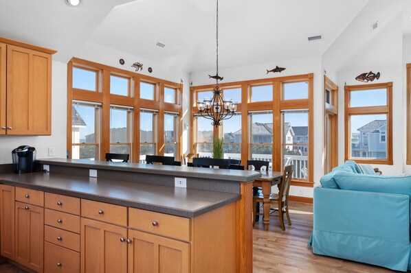 A spacious kitchen with large windows, wooden cabinets, and a central island. - Piggy's Paradise-Oceanside, community pool, private hot tub, short walk to the beach! (Nags Head)