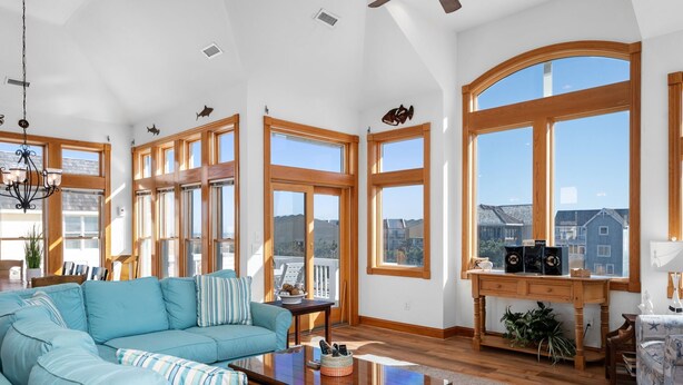 Un salón amplio con un gran sofá modular, piso de madera y ventanas grandes que dan al vecindario.