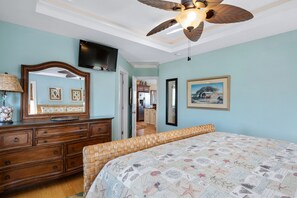 Une chambre à coucher avec un lit, une commode en bois et un ventilateur de plafond.