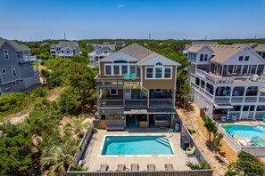 A two-story house with a swimming pool, a deck, and a patio area.
