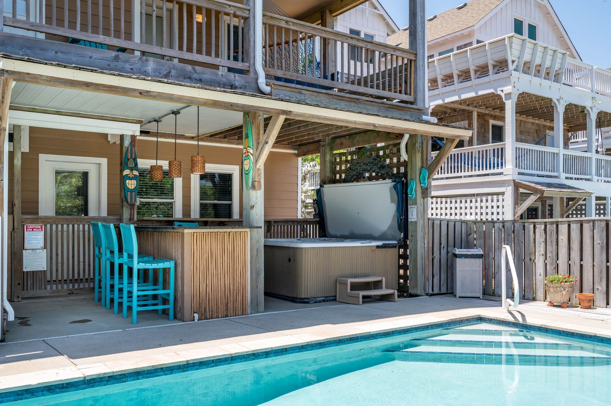 Un espace piscine doté d’un jacuzzi, d’une terrasse en bois et de coins salon extérieurs.