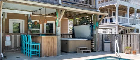 A pool area with a hot tub, wooden deck, and outdoor seating.