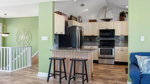 Una cocina moderna con una isla central, electrodomésticos de acero inoxidable y armarios de colores claros.