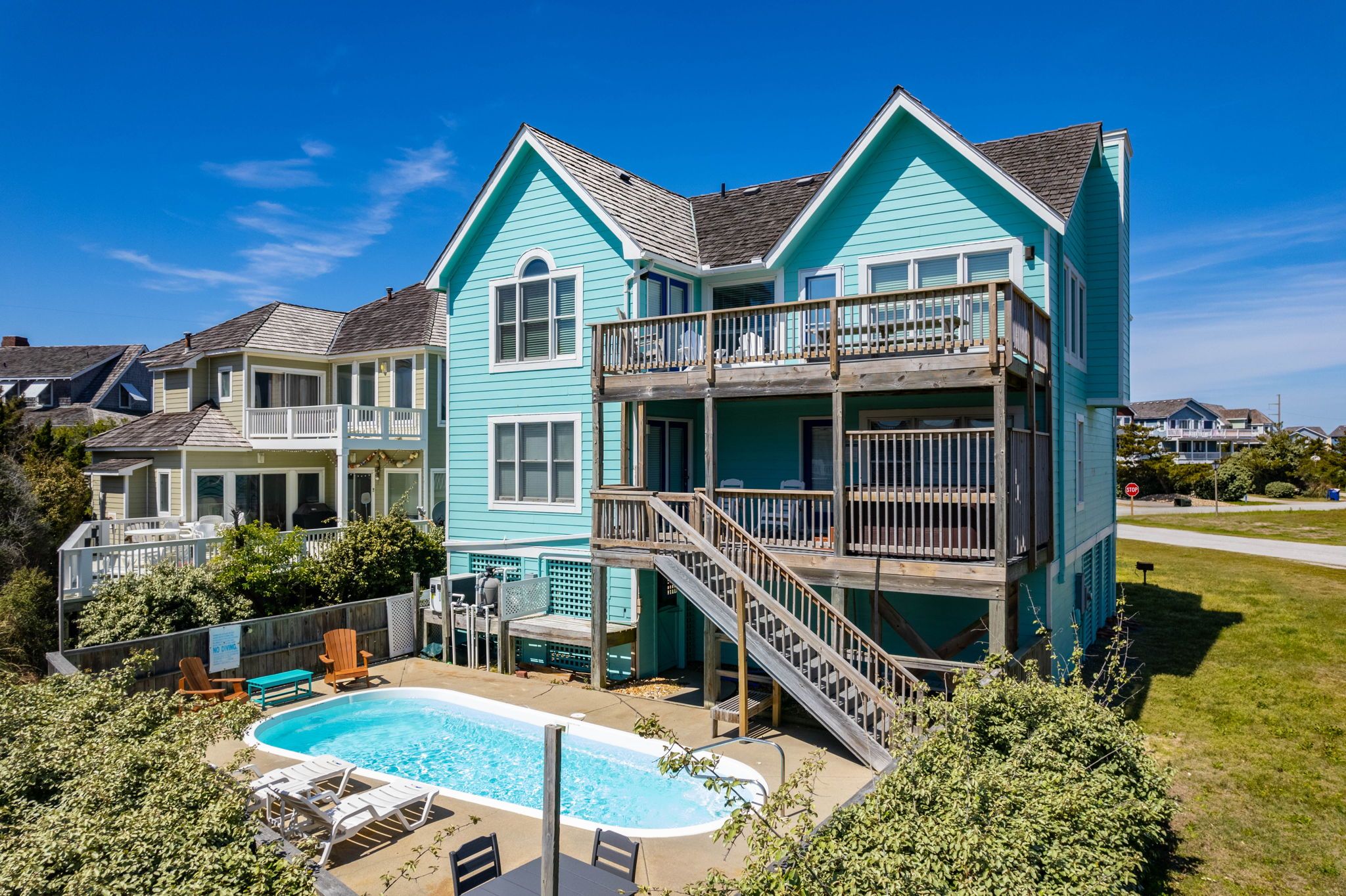 A two-story house with a swimming pool, a deck, and a staircase leading to a balcony.