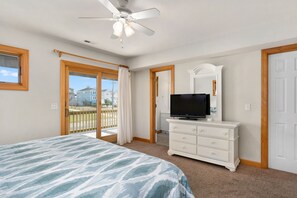 A bedroom with a bed, a dresser, a television, and a ceiling fan.