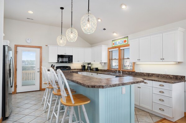 A kitchen with white cabinets, a granite countertop, and a bar area with stools.