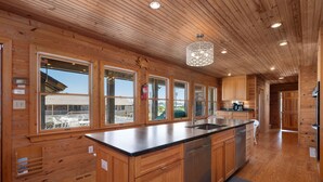 Ein Holzblockhaus-Innenraum mit einer Küche, die eine zentrale Kochinsel, Holzausstattung und große Fenster bietet.