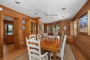 Ein Holzinterieur mit einem Esstisch, Stühlen, einem Deckenventilator und einer Küchenzeile.