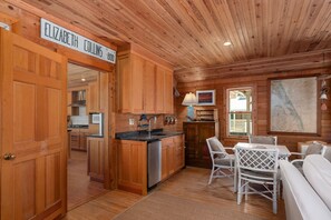 Un intérieur en bois comprenant une cuisine, un coin repas et une enseigne portant l’inscription « ELIZABETH COLLINS ».