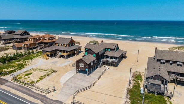 Ein Strandhotel mit mehreren Gebäuden, einem Sandstrand und dem Meer im Hintergrund.