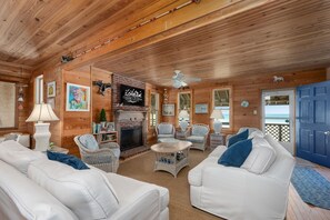 Un intérieur de chalet chaleureux avec une cheminée, des meubles en osier et une porte bleue.