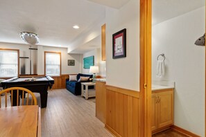 A room with a pool table, a blue sofa, a lamp, and a framed picture on the wall.