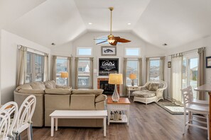 A spacious living room with a large sofa, a dining table, and a fireplace.