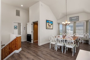 A spacious kitchen with a wooden countertop and a dining area with white chairs and a wooden table.