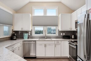 A modern kitchen with white cabinets, a stainless steel dishwasher, and a built-in oven.