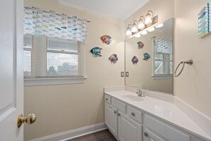 Un baño con lavamanos, espejo y decoración de peces en la pared.