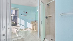 A bathroom with a glass shower, a bathtub, and a window.