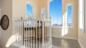 Una habitación amplia con un gran ventanal, una escalera de madera y vistas al exterior.