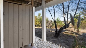 A covered outdoor area with a wooden deck and a view of a natural landscape. - Wedges 13: Soundside, 13th fairway view, great community pool and tennis courts. ⛳☀️ (Nags Head)