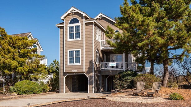 A two-story house with a balcony, a garage, and a driveway. - Wedges 13: Soundside, 13th fairway view, great community pool and tennis courts. ⛳☀️ (Nags Head)