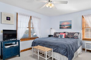 A bedroom with a bed, a TV, a desk, and a window with curtains. - Wedges 13: Soundside, 13th fairway view, great community pool and tennis courts. ⛳☀️ (Nags Head)