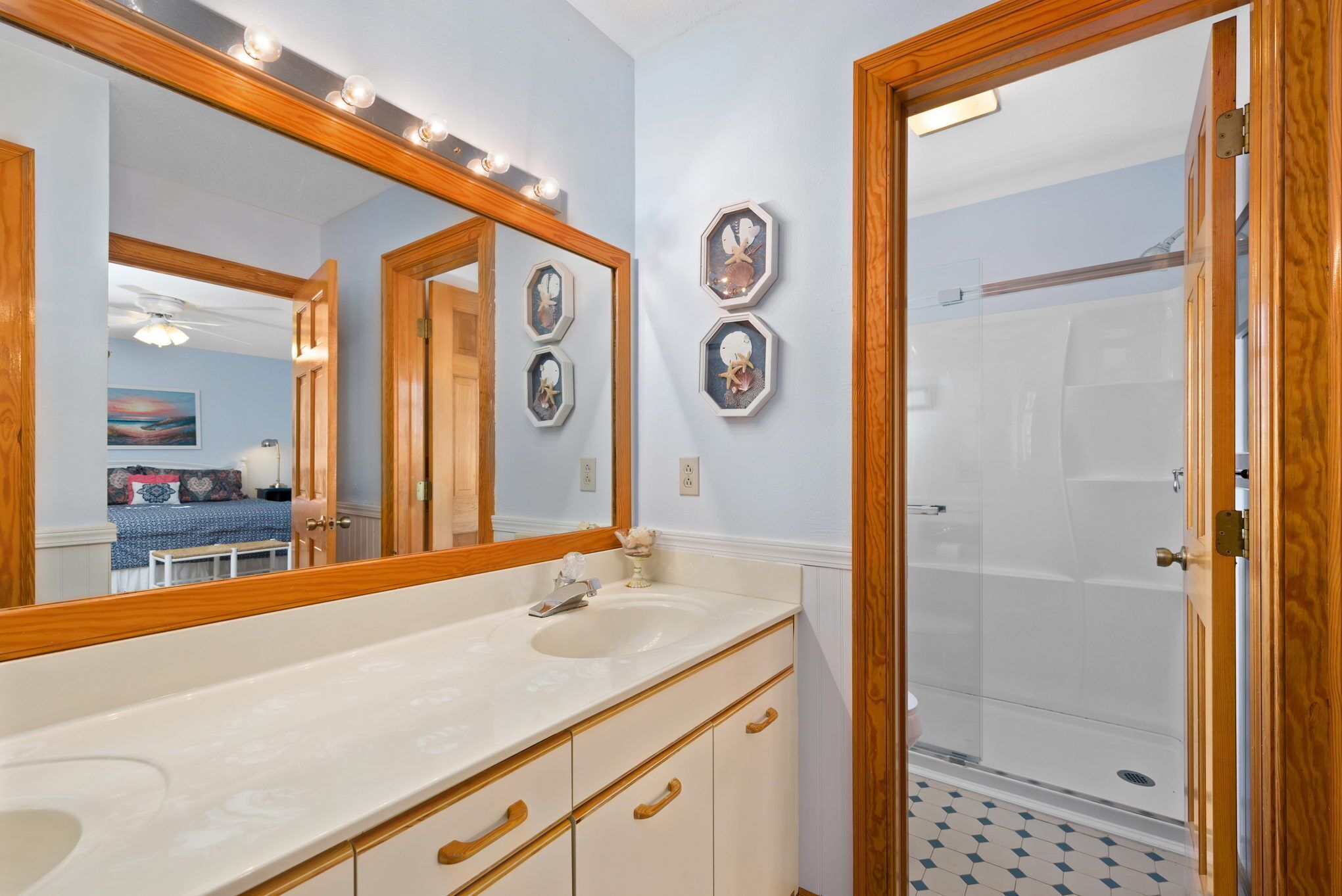 Une salle de bain dotée d’un grand miroir, d’un meuble-lavabo et d’une cabine de douche en verre.