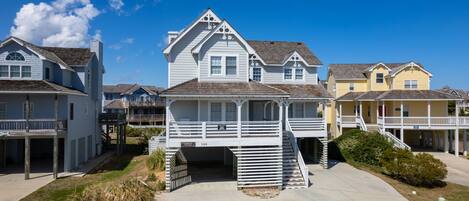 A beachfront house with a covered porch and a small staircase leading to a deck.