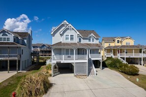 Une maison située en bord de mer, dotée d’un porche couvert et d’un petit escalier menant à une terrasse.