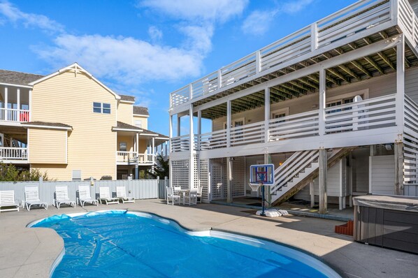 Un espace piscine comprenant un terrain de basketball, des chaises longues et un jacuzzi.