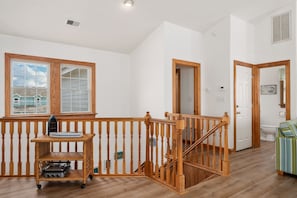 A spacious room with a wooden staircase, a window with a view, and a small table with a radio.