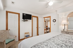 A bedroom with a bed, a television, a chair, and a lamp.