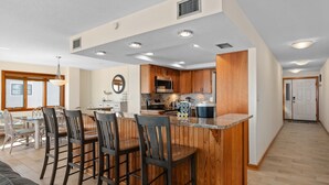 Una cocina moderna con armarios de madera, una isla central con taburetes de bar y una zona de comedor con mesa y sillas.