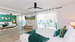 Een moderne slaapkamer met een groot bed, een plafondventilator, een televisie en uitzicht op een stadsbeeld door het raam.