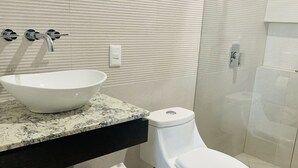 Casa de banho com lavatório branco, sanita e zona de duche.